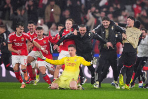 Benfica players celebrate a victory after a penalty shootout during a competitive football match.
